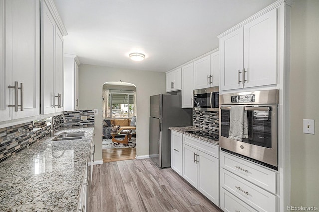 4051 S Cherokee St, Englewood, CO 80110 - kitchen featuring stainless steel appliances, arched walkways, decorative backsplash, and white cabinetry