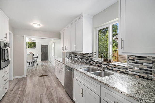 4051 S Cherokee St, Englewood, CO 80110 - kitchen with appliances with stainless steel finishes, tasteful backsplash, white cabinetry, light wood-type flooring, and light stone counters