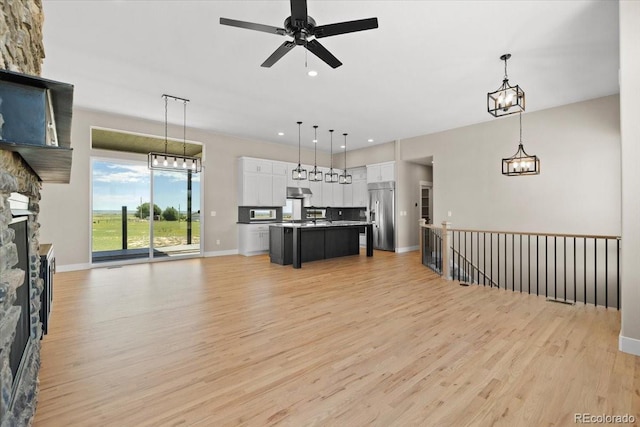 interior space featuring light wood-type flooring, white cabinetry, a center island, and high end refrigerator