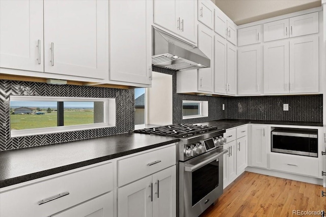 kitchen with light hardwood / wood-style floors, stainless steel appliances, decorative backsplash, and white cabinets