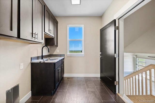 kitchen with sink, dark brown cabinetry, and dark tile patterned floors