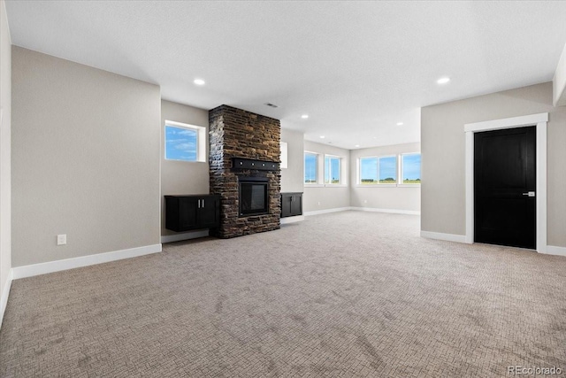 unfurnished living room with light carpet, a fireplace, and a textured ceiling