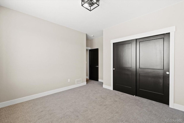 unfurnished bedroom with light colored carpet and a closet