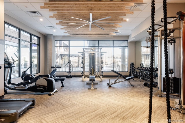 workout area with ceiling fan, a paneled ceiling, and plenty of natural light