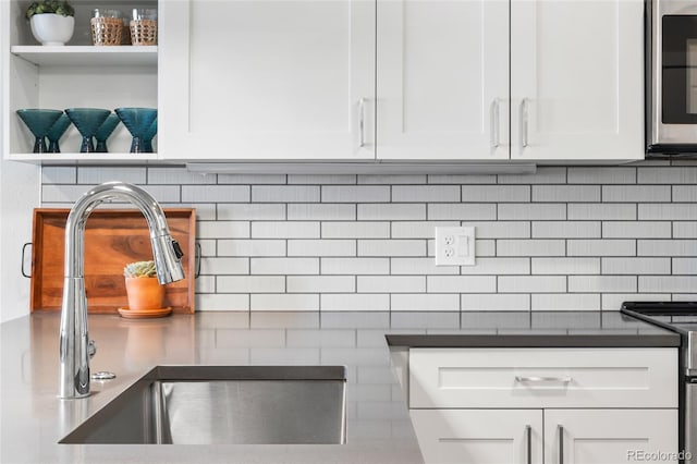 room details featuring white cabinetry, appliances with stainless steel finishes, sink, and decorative backsplash