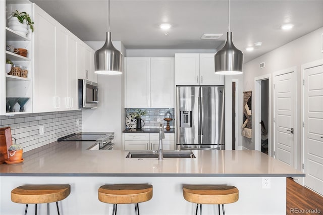 kitchen featuring stainless steel appliances, sink, white cabinets, and a kitchen breakfast bar