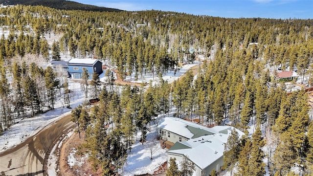 snowy aerial view featuring a wooded view