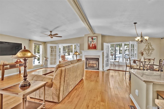 living room featuring lofted ceiling with beams, light wood-style floors, a fireplace with flush hearth, and baseboards