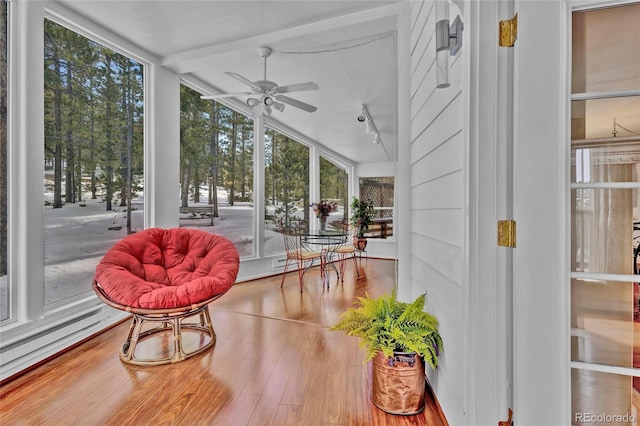 sunroom featuring track lighting, baseboard heating, and a ceiling fan