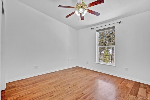 spare room with hardwood / wood-style floors, a ceiling fan, and baseboards