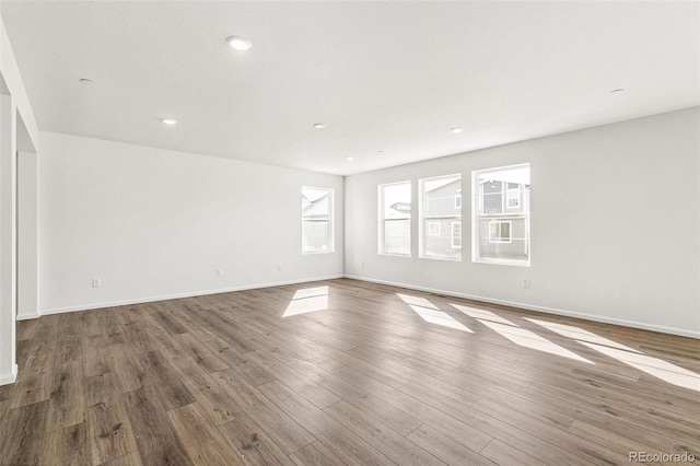 empty room featuring recessed lighting, wood finished floors, and baseboards