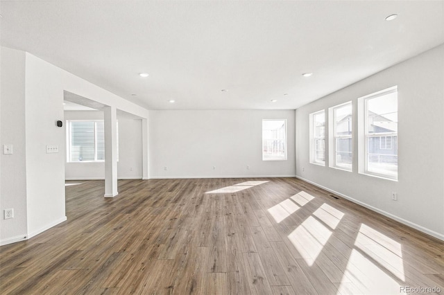 unfurnished room featuring plenty of natural light, baseboards, and wood finished floors