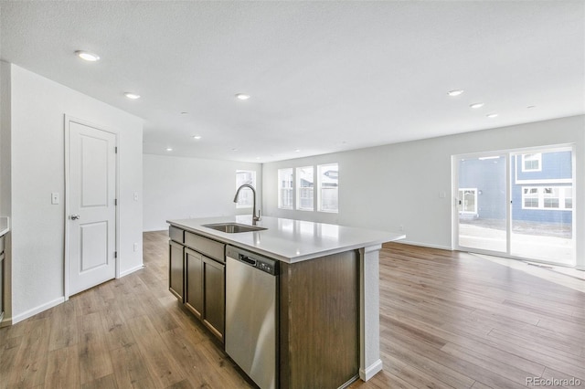 kitchen with dishwasher, open floor plan, a sink, and light wood-style flooring