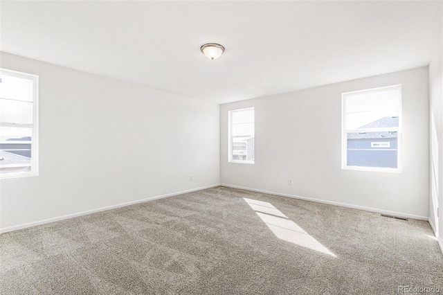 spare room featuring visible vents, baseboards, and carpet flooring