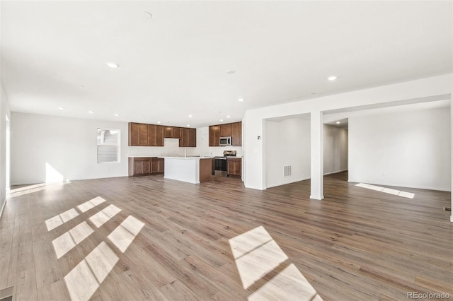 unfurnished living room featuring recessed lighting, visible vents, baseboards, and wood finished floors