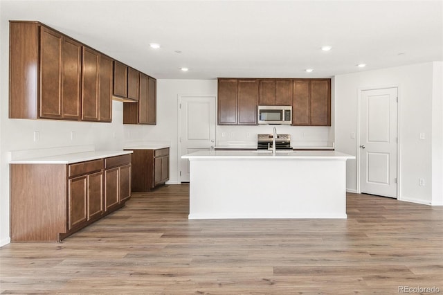 kitchen featuring an island with sink, light wood-style floors, stainless steel appliances, and recessed lighting