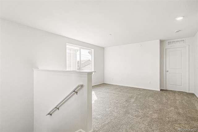 carpeted spare room with visible vents and baseboards