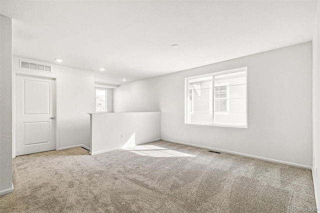 carpeted empty room featuring baseboards, visible vents, and recessed lighting