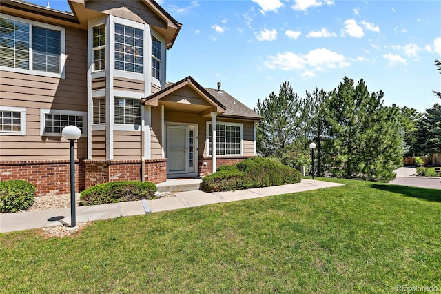 view of front facade with brick siding and a front yard