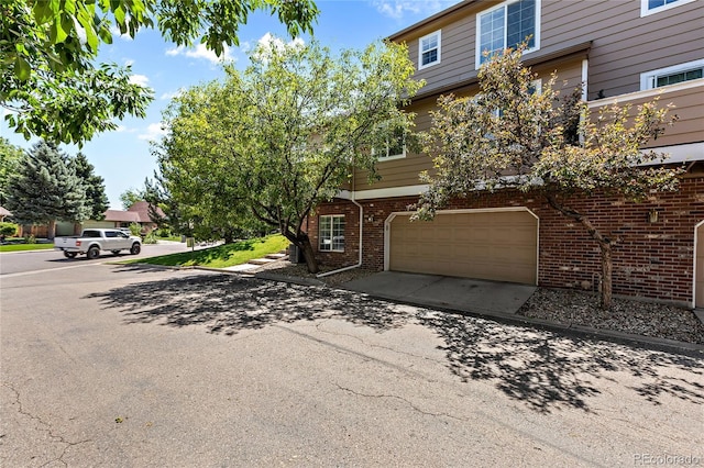 view of property featuring brick siding, driveway, and an attached garage