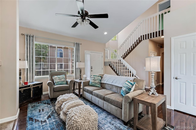 living area with stairs, a ceiling fan, baseboards, and wood finished floors