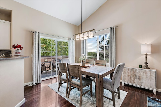 dining space with high vaulted ceiling, dark wood-style flooring, and baseboards