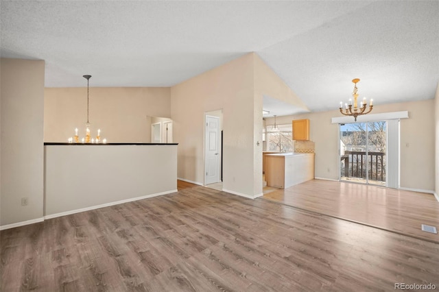 unfurnished living room featuring vaulted ceiling, a notable chandelier, and hardwood / wood-style floors