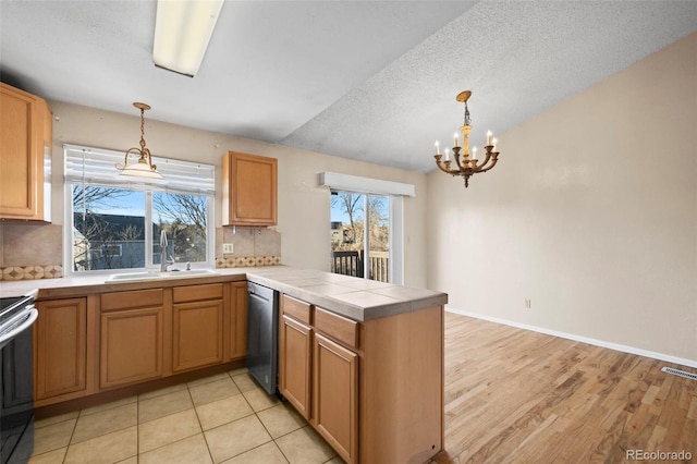 kitchen featuring stainless steel dishwasher, decorative backsplash, kitchen peninsula, sink, and hanging light fixtures