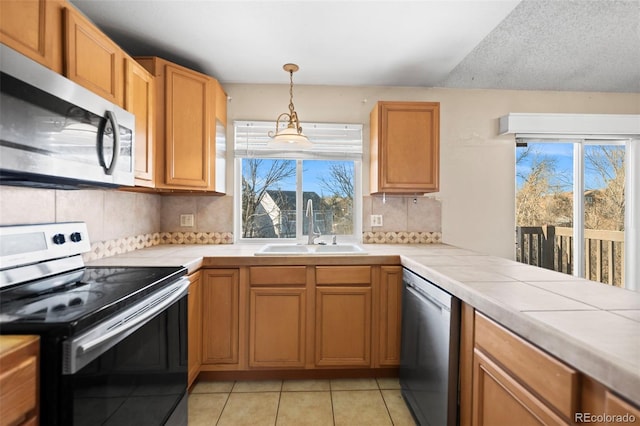 kitchen with appliances with stainless steel finishes, tasteful backsplash, sink, tile countertops, and light tile patterned floors