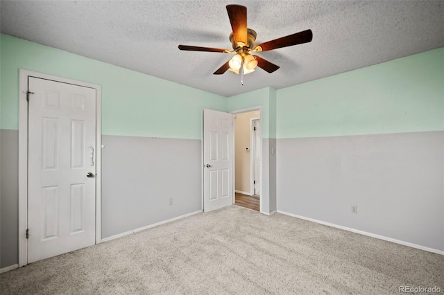 unfurnished bedroom featuring ceiling fan, light colored carpet, and a textured ceiling