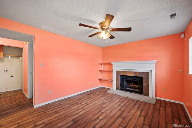 unfurnished living room with a textured ceiling, ceiling fan, dark hardwood / wood-style flooring, and a fireplace