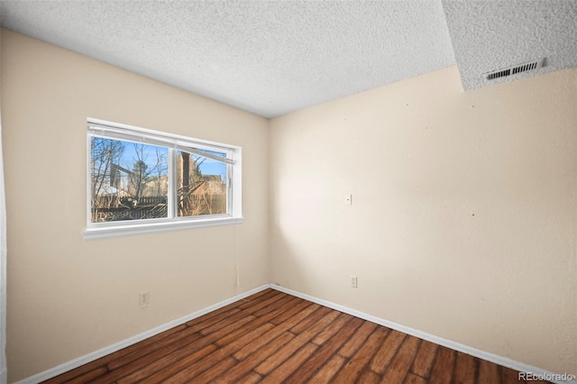 empty room featuring a textured ceiling and hardwood / wood-style floors