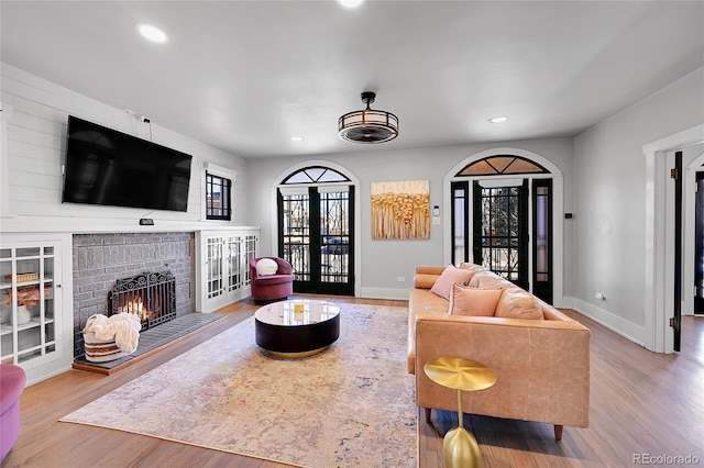 living room featuring recessed lighting, baseboards, wood finished floors, and a fireplace