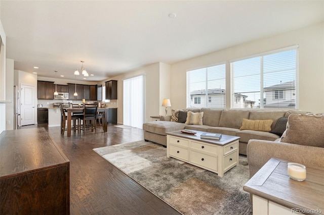 living area with a notable chandelier, plenty of natural light, recessed lighting, and dark wood-style floors