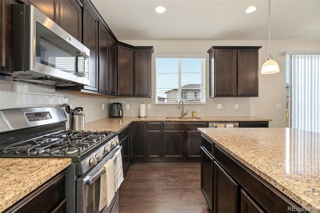kitchen with dark wood finished floors, appliances with stainless steel finishes, decorative backsplash, and a sink