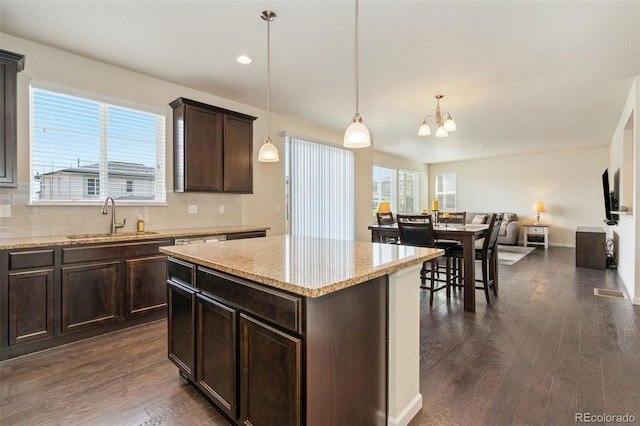 kitchen with dark brown cabinets, dark wood-style flooring, open floor plan, and a sink