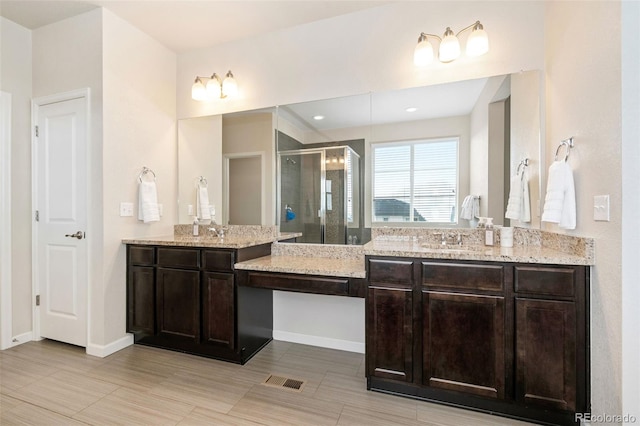 full bathroom with baseboards, a stall shower, two vanities, and a sink