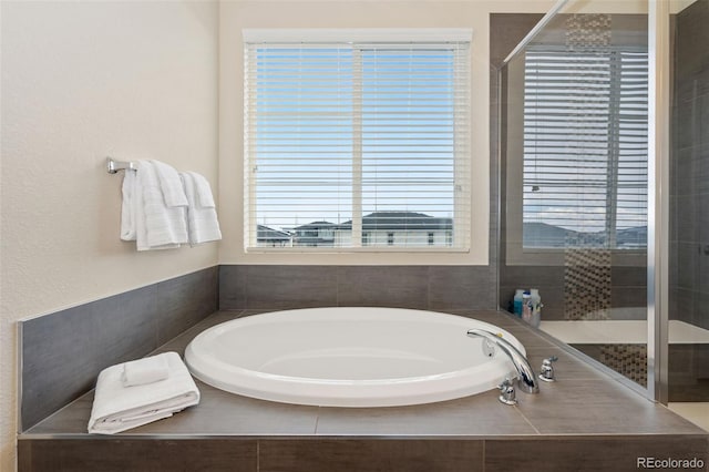 bathroom with a bath and tiled shower