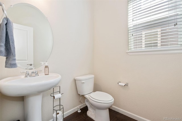 bathroom featuring wood finished floors, baseboards, toilet, and a sink