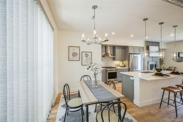 4922 Lowell Blvd Unit 3, Denver, CO 80221 - kitchen featuring appliances with stainless steel finishes, gray cabinets, wall chimney exhaust hood, light wood-style floors, and light countertops