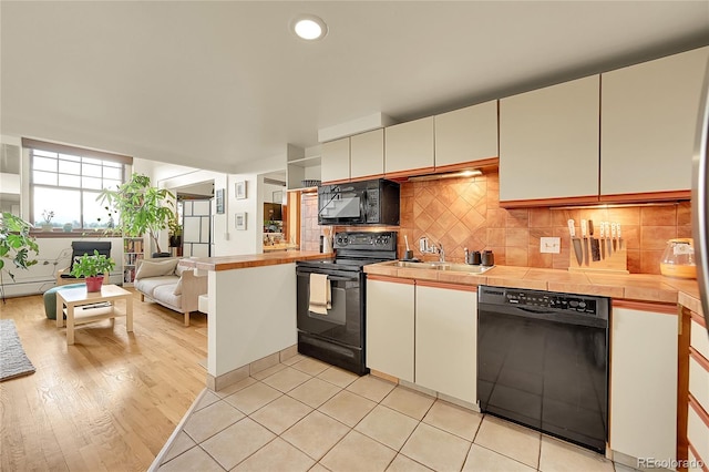 2351 Federal Blvd Unit 401, Denver, CO 80211 - kitchen featuring black appliances, decorative backsplash, open floor plan, tile counters, and white cabinets