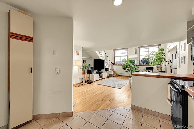 2351 Federal Blvd Unit 401, Denver, CO 80211 - kitchen featuring black / electric stove, tile counters, a baseboard radiator, and light tile patterned floors