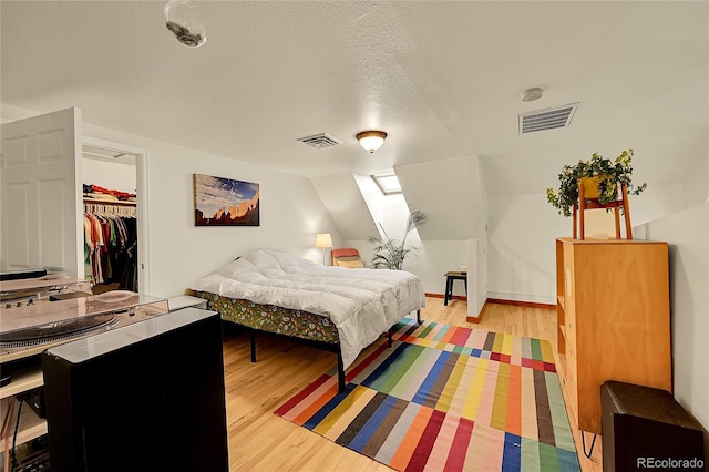 2351 Federal Blvd Unit 401, Denver, CO 80211 - bedroom with light wood-style floors, a walk in closet, a closet, and a textured ceiling