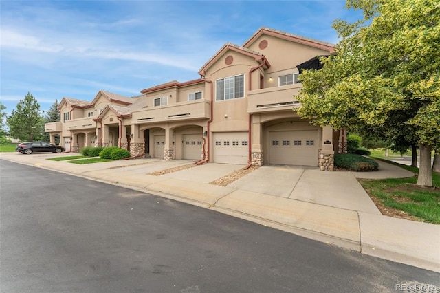 10760 Eliot Cir Unit 204, Denver, CO 80234 - view of front of property with stucco siding, stone siding, driveway, a garage, and a balcony