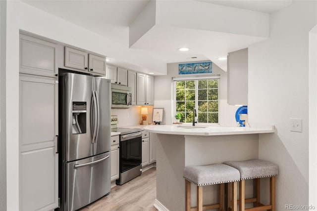 10760 Eliot Cir Unit 204, Denver, CO 80234 - kitchen with appliances with stainless steel finishes, a breakfast bar area, tasteful backsplash, light wood-style floors, and a peninsula