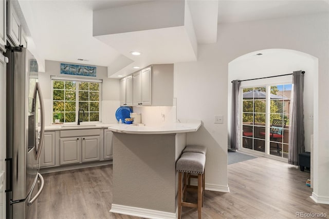 10760 Eliot Cir Unit 204, Denver, CO 80234 - kitchen with stainless steel refrigerator with ice dispenser, light wood-style floors, a kitchen bar, a peninsula, and recessed lighting