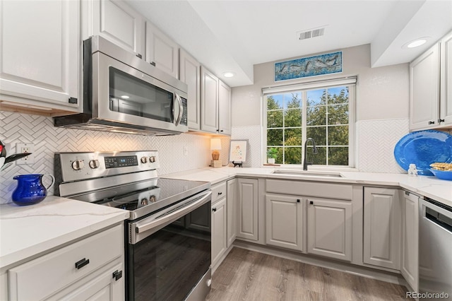 10760 Eliot Cir Unit 204, Denver, CO 80234 - kitchen with appliances with stainless steel finishes, decorative backsplash, light wood-type flooring, recessed lighting, and light stone countertops