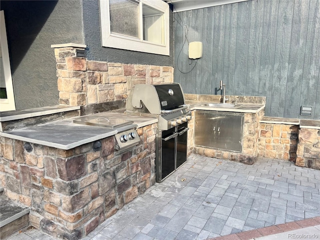 view of patio with area for grilling, sink, and exterior kitchen