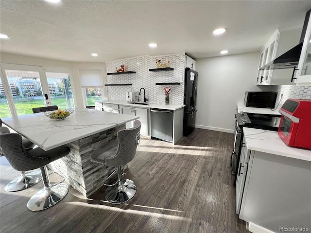 kitchen with dark hardwood / wood-style floors, sink, backsplash, black appliances, and white cabinetry