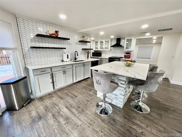 kitchen with a kitchen island, decorative backsplash, dark wood-type flooring, sink, and wall chimney range hood